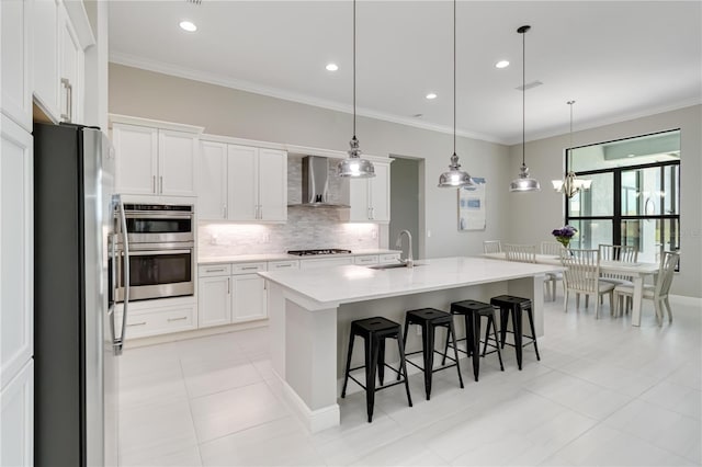 kitchen with tasteful backsplash, crown molding, a sink, wall chimney range hood, and appliances with stainless steel finishes