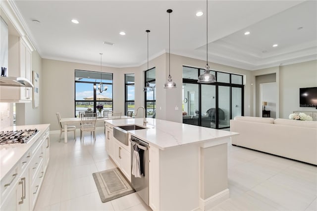 kitchen with crown molding, stainless steel appliances, a sink, an island with sink, and light stone countertops