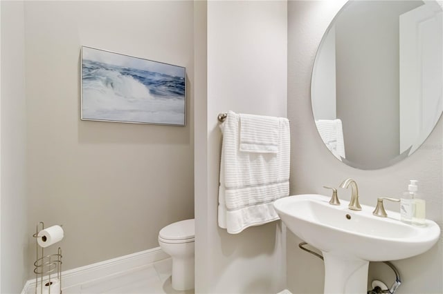 bathroom with toilet, a sink, and baseboards