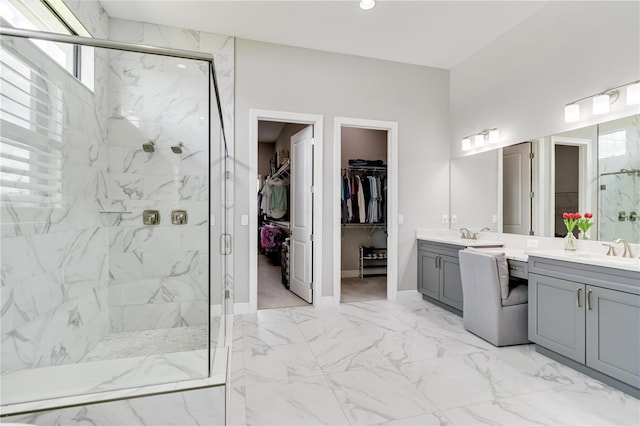 bathroom featuring vanity, a marble finish shower, a spacious closet, marble finish floor, and baseboards