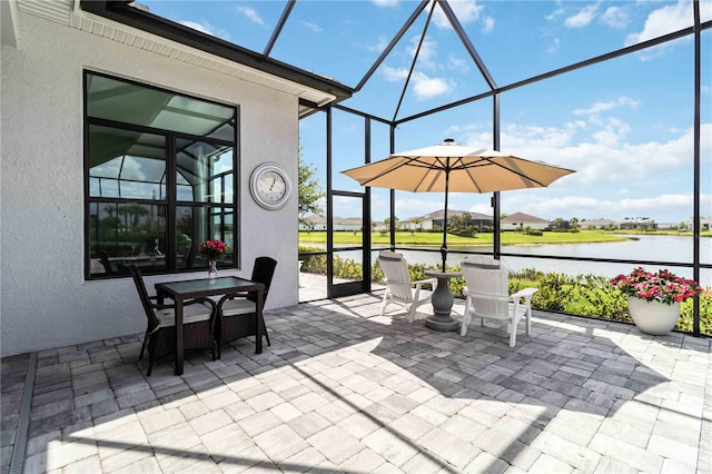 view of patio with a lanai, a water view, and outdoor dining area