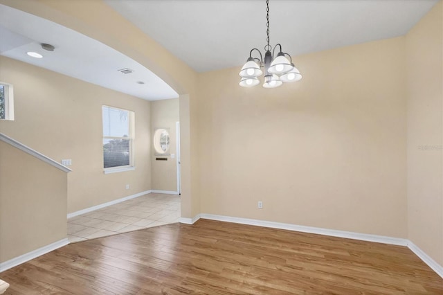 1085 Jonah Dr, North Port, FL 34289 - unfurnished room with baseboards, wood finished floors, arched walkways, and an inviting chandelier