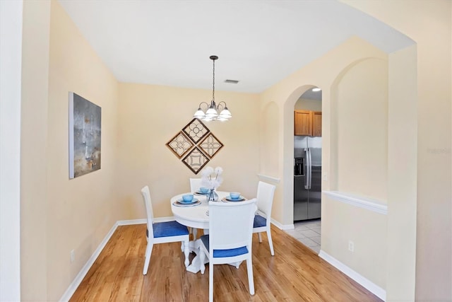 1085 Jonah Dr, North Port, FL 34289 - dining room with arched walkways, light wood-type flooring, and a chandelier