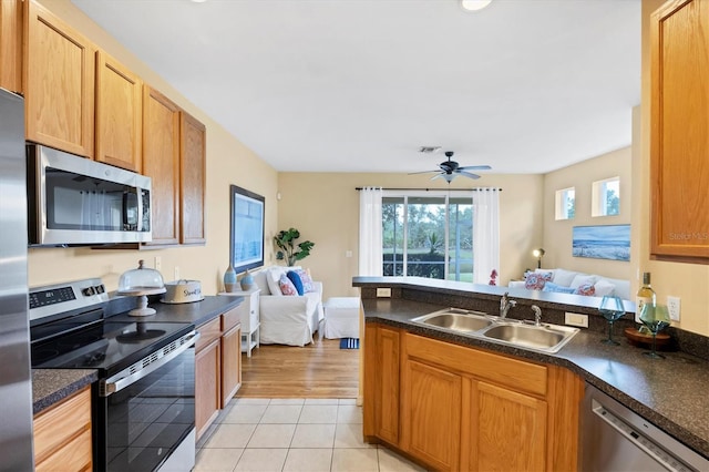 1085 Jonah Dr, North Port, FL 34289 - kitchen with stainless steel appliances, open floor plan, dark countertops, a peninsula, and light tile patterned floors