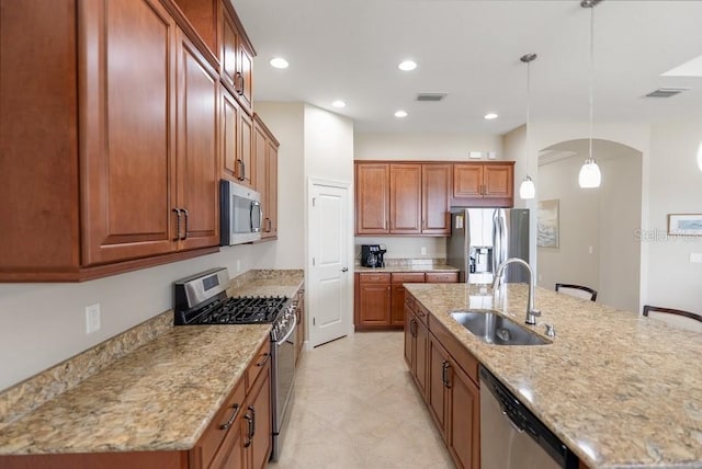kitchen with visible vents, appliances with stainless steel finishes, light stone counters, a sink, and hanging light fixtures