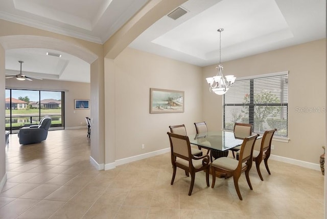 dining room featuring a tray ceiling, arched walkways, baseboards, and visible vents