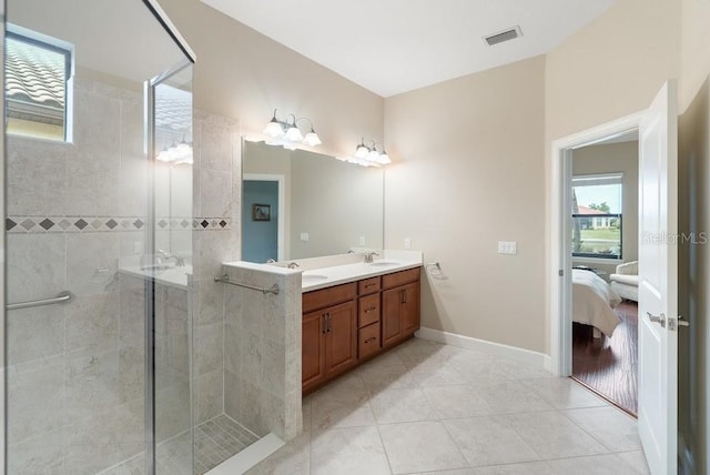 full bath with double vanity, ensuite bathroom, tiled shower, visible vents, and a sink