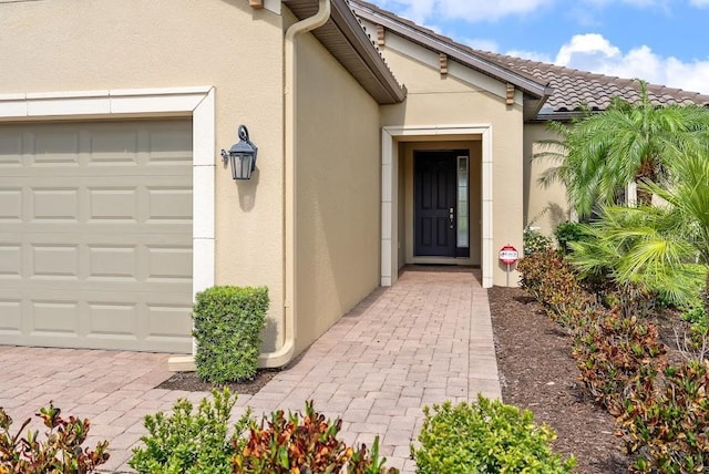 entrance to property featuring a garage and stucco siding