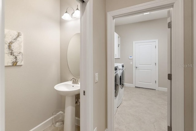 bathroom with washing machine and dryer, baseboards, and a sink