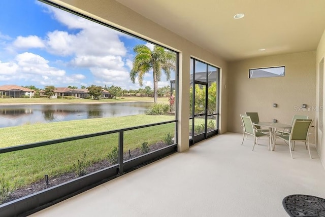 sunroom featuring carpet and a water view