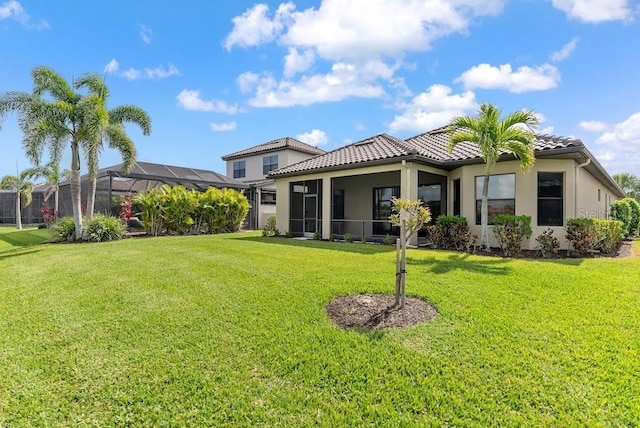 back of house with a lanai, a yard, stucco siding, and a tiled roof