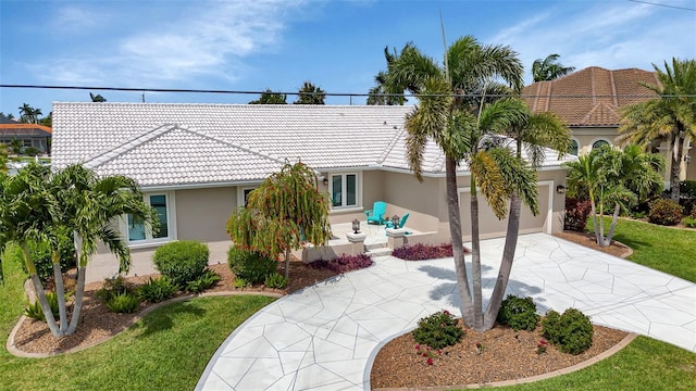 view of front of house with concrete driveway, stucco siding, a tile roof, and a garage