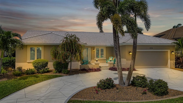 view of front of house featuring a tiled roof, driveway, stucco siding, and a garage