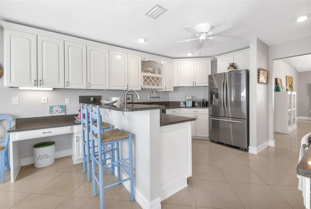 kitchen with stainless steel fridge with ice dispenser, light tile patterned floors, a peninsula, white cabinetry, and visible vents