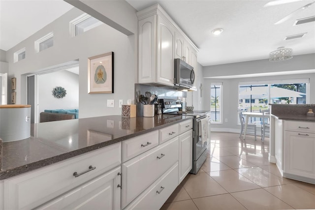 kitchen with white cabinets, visible vents, light tile patterned flooring, stainless steel microwave, and electric range oven