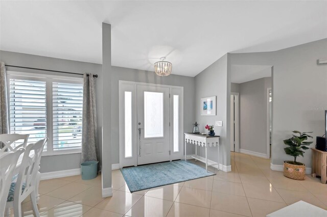 foyer entrance featuring light tile patterned floors, baseboards, and an inviting chandelier