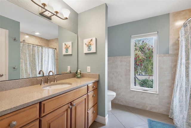 bathroom with a shower with shower curtain, vanity, tile patterned flooring, toilet, and tile walls