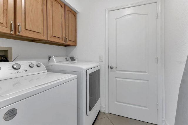 clothes washing area with light tile patterned floors, washing machine and dryer, and cabinet space