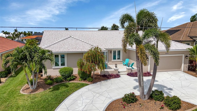 view of front of property with concrete driveway, stucco siding, an attached garage, a front yard, and a tiled roof