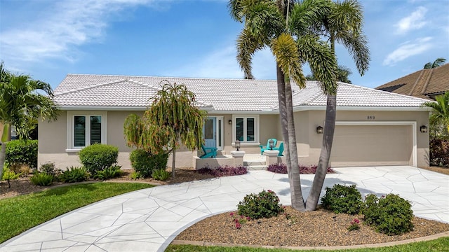 ranch-style home with concrete driveway, a tiled roof, an attached garage, and stucco siding
