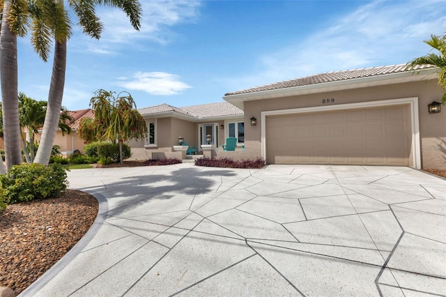view of front facade with concrete driveway, a tile roof, a garage, and stucco siding