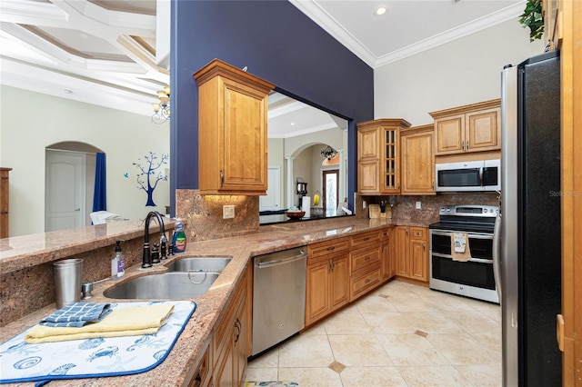kitchen featuring appliances with stainless steel finishes, a sink, ornamental molding, and arched walkways