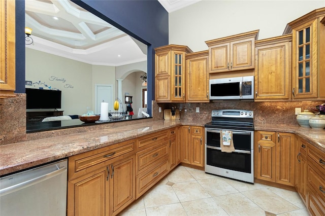 kitchen with arched walkways, appliances with stainless steel finishes, crown molding, and decorative backsplash