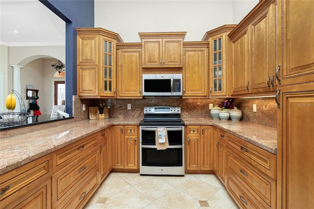 kitchen featuring light tile patterned floors, arched walkways, appliances with stainless steel finishes, and decorative backsplash