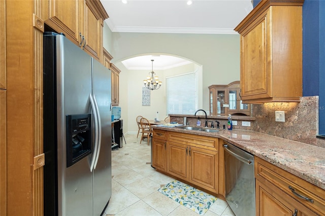 kitchen with tasteful backsplash, arched walkways, appliances with stainless steel finishes, a sink, and crown molding