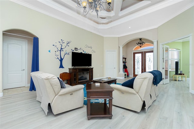 living room with arched walkways, an inviting chandelier, light wood-style flooring, decorative columns, and french doors
