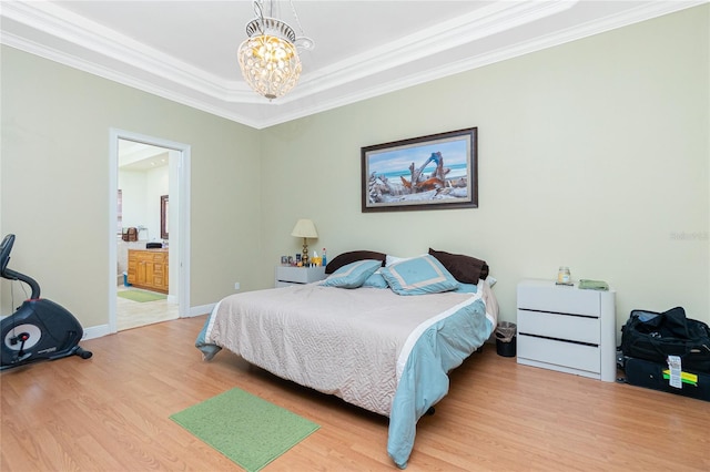 bedroom featuring crown molding, an inviting chandelier, wood finished floors, and ensuite bath