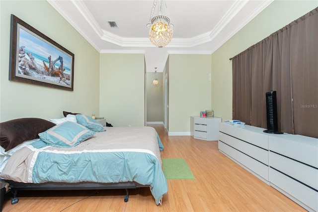 bedroom featuring wood finished floors, an inviting chandelier, visible vents, a raised ceiling, and crown molding
