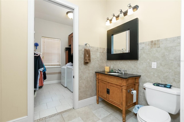 bathroom featuring washer and dryer, toilet, tile walls, tile patterned floors, and vanity