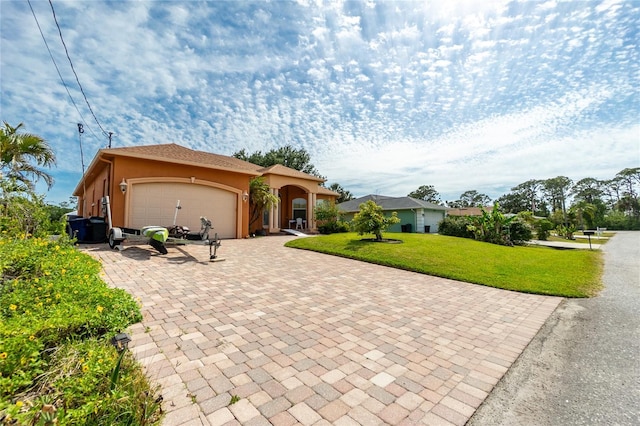 view of front facade with a garage, stucco siding, a front yard, and decorative driveway