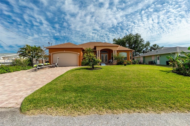 view of front of property with decorative driveway, stucco siding, french doors, a front lawn, and a garage