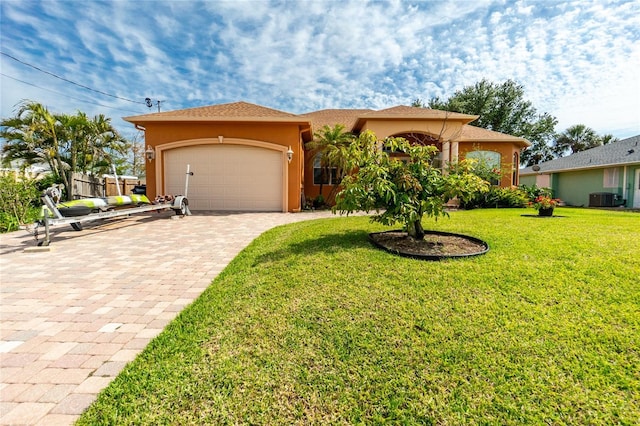 mediterranean / spanish-style home with a front lawn, a garage, cooling unit, decorative driveway, and stucco siding