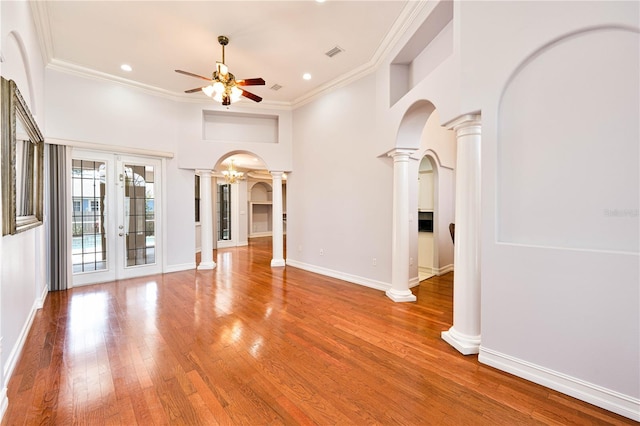 8315 Raoul Ave, North Port, FL 34291 - unfurnished living room featuring arched walkways, decorative columns, ceiling fan, wood finished floors, and ornamental molding