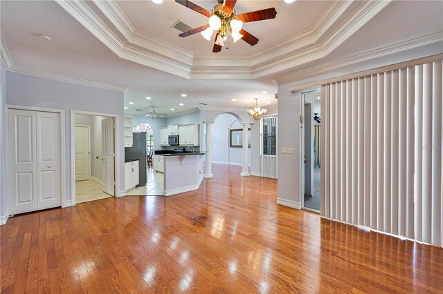 8315 Raoul Ave, North Port, FL 34291 - unfurnished living room with a ceiling fan, a raised ceiling, ornamental molding, light wood finished floors, and decorative columns