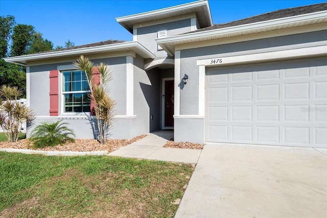 3476 Brewster Rd, North Port, FL 34288 - view of exterior entry with a garage, stucco siding, and driveway
