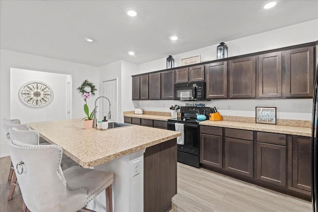 3476 Brewster Rd, North Port, FL 34288 - kitchen with light wood-type flooring, a sink, black appliances, and dark brown cabinets