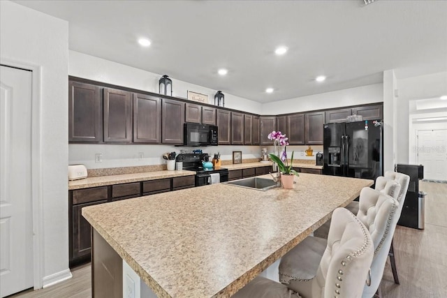 3476 Brewster Rd, North Port, FL 34288 - kitchen with a center island with sink, a breakfast bar area, black appliances, and dark brown cabinetry