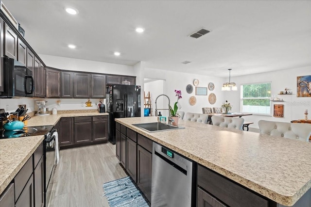 3476 Brewster Rd, North Port, FL 34288 - kitchen with dark brown cabinetry, visible vents, black appliances, light countertops, and a sink