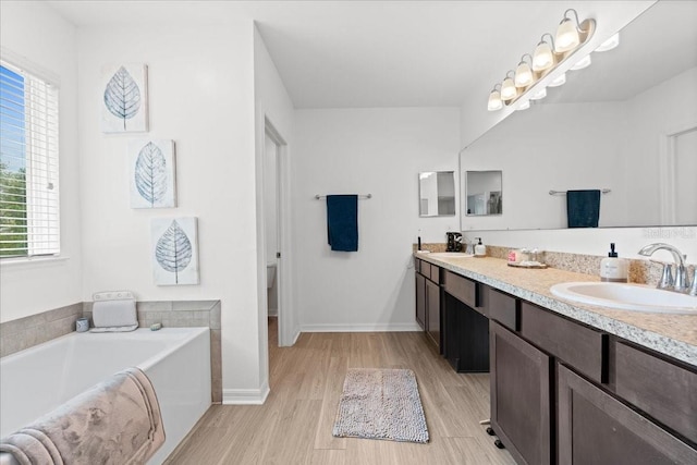 3476 Brewster Rd, North Port, FL 34288 - full bathroom with baseboards, a sink, double vanity, wood finished floors, and a garden tub