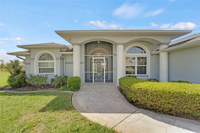 229 Sportsman Rd, Rotonda West, FL 33947 - view of exterior entry with stucco siding and a lawn