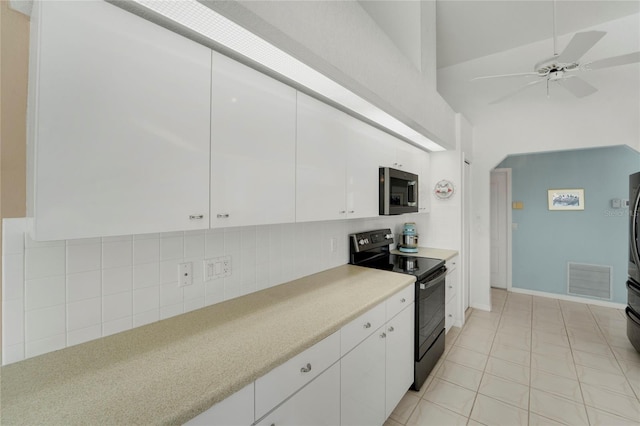 229 Sportsman Rd, Rotonda West, FL 33947 - kitchen with black electric range, white cabinetry, stainless steel microwave, and decorative backsplash