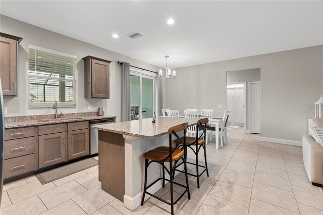 2229 Wakefield St, Port Charlotte, FL 33948 - kitchen featuring a sink, a chandelier, light stone counters, light tile patterned floors, and a center island