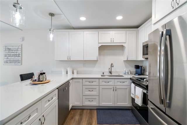 kitchen featuring white cabinets, dark wood-style flooring, a sink, light countertops, and stainless steel appliances