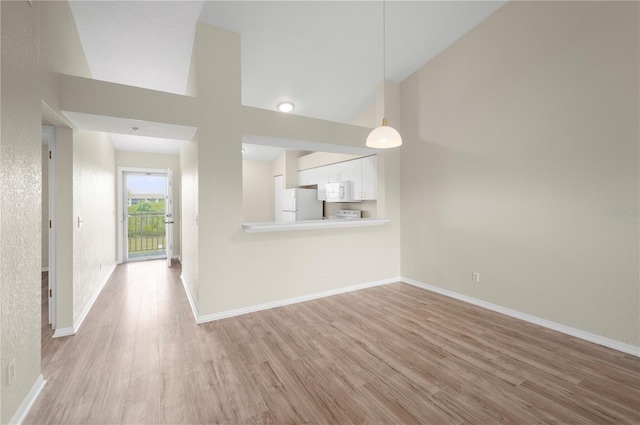 175 Kings Hwy Unit B21522, Punta Gorda, FL 33983 - unfurnished living room featuring baseboards, light wood-type flooring, and a high ceiling