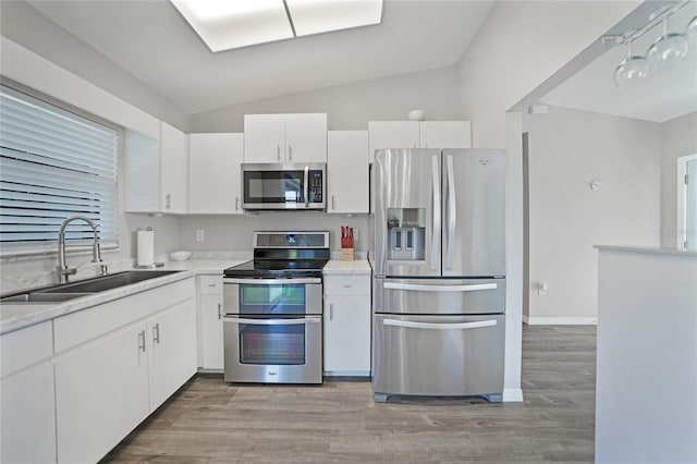 2621 Larkspur Dr, Punta Gorda, FL 33950 - kitchen featuring white cabinets, appliances with stainless steel finishes, a sink, lofted ceiling, and light wood finished floors