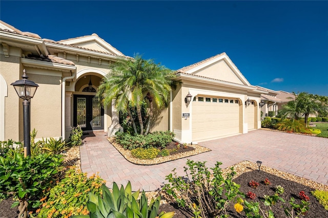 view of front of home featuring an attached garage, stucco siding, and decorative driveway